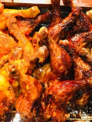 top-down close-up of a heap of roasted chicken thighs. The meat appears succulent and is coated in a rich, dark seasoning. This results in a deep, reddish-brown, glistening skin