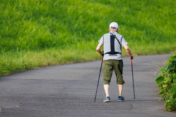 体力維持のためストックを持って散歩をする高齢男性