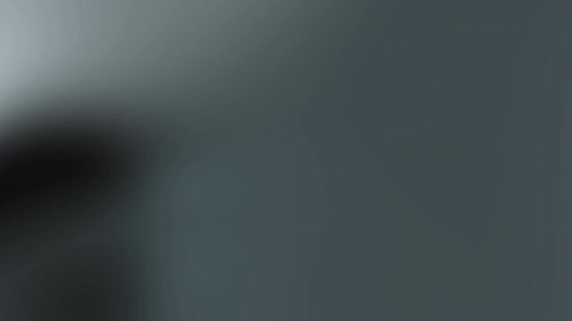 Blurred gray gradient background with a dark smudge ideal for minimalist designs, abstract concepts, or creative backgrounds for various graphic projects.