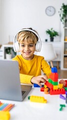 Joyful young boy with headphones intently building with colorful blocks while engaging with a laptop, fostering creativity and learning in a bright, modern home environment.