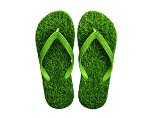 Two green flip-flops, crafted from lush green grass, sit on a dark background
