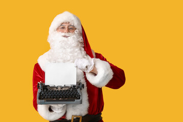 Santa Claus with vintage typewriter on yellow background