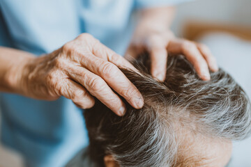 Naklejka premium Close up hands examining senior patient hair and scalp care