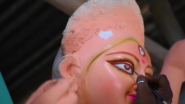 An artiest has been drawing and painting eyes of goddess Durga. Clay idol of Hindu goddess Durga is under preparation.