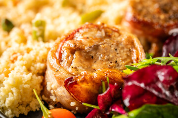 Closeup of pork medallion with couscous and salad