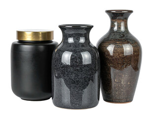Three ceramic vases on black, one with a gold lid, diverse shapes and glazes
