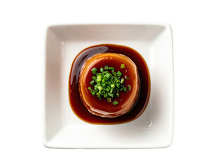 Top-down shot of stacked savory dish in a white square bowl, garnished with chives