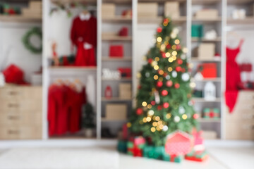 Modern wardrobe with stylish festive clothes, gift boxes and Christmas tree, blurred view