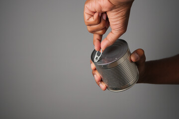 Hand opening a can with a pull tab for easy access