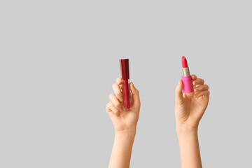 Female hands with lipsticks on light background
