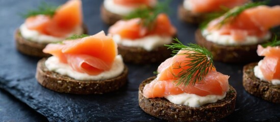 Delicious appetizers with smoked salmon, cream cheese on rye bread, elegantly arranged on a slate board.