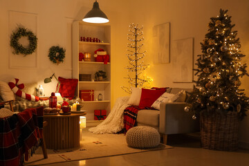 Interior of dark living room with glowing lamps, Christmas tree and sofa
