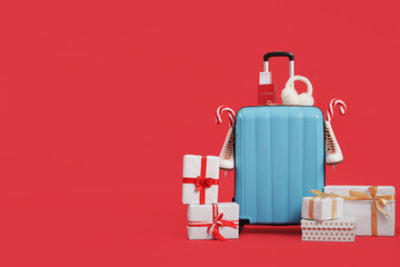 Suitcase with ice skates, winter headphones and Christmas gifts on red background. Travel concept