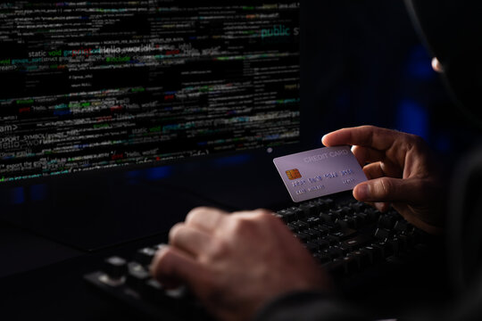 Cropped hands image in criminal anonymous male approaching credit card of personal information database for codding encryption scam program in privacy system at night at blue neon light room. Surmise.