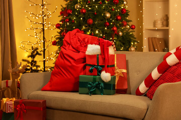 Santa bag with Christmas presents on sofa in living room at night