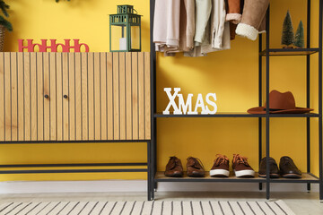 Shelf unit with word XMAS, hat and shoes in hallway
