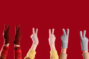 Women in warm gloves showing victory gesture on red background