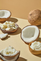 Still life photography with coconut shells, creamy shea butter, and leaf accent, styled for spa, beauty, and skincare product advertising with minimal background.