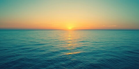Obraz premium A serene sunset over the ocean, with the sun setting behind a horizon line, casting a warm glow over the water and a calm sea.
