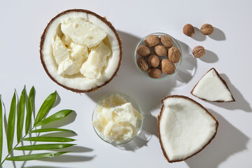 Fresh coconut pieces, creamy shea butter, and nuts styled with green leaf on white background. Scene for a natural beauty theme, perfect for organic cosmetic ads and skincare product visuals.