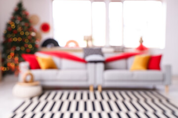 Blurred view of living room decorated for Japanese New Year celebration with sofas and fir tree