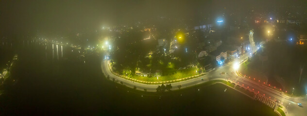 Aerial view of a Da Lat City, Vietnam in the mist magical night, hiden in the fog and clouds. Urban development texture, transport infrastructure. Tourist city in developed Vietnam.