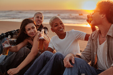 Friends drinking beer and enjoying sunset at the beach