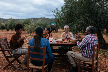 Farmers celebrating harvest with outdoor dinner in olive grove