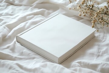 Serene white book rests on soft white sheets delicate dried flowers nearby minimalist aesthetic clean design pure white