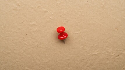 Fototapeta premium Red pin placed on textured brown paper, highlighting simplicity and focus, perfect for concepts of planning, reminders, or marking important points.