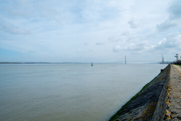 A tranquil and serene river landscape brilliantly showcasing distant structures set against a cloudy sky