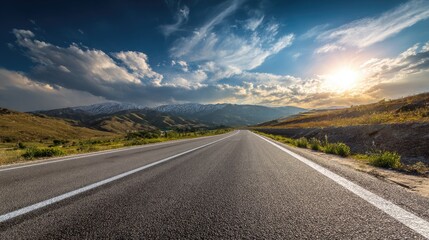 Naklejka premium Empty asphalt road stretches into a mountain range at sunset