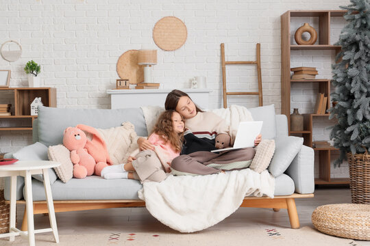 Cute sisters with laptop watching cartoons at home on winter day - Powered by Adobe