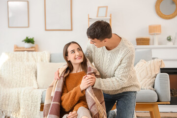 Loving young happy couple with plaid sitting on floor at home
