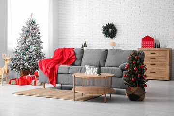 Interior of living room with Christmas trees, sofa and table
