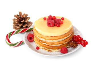 Plate of sweet pancakes with berries, pine cone and Christmas candy cane on white background