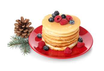 Plate of sweet pancakes with berries, pine cone and Christmas tree branch on white background