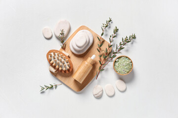 Composition with essential oil, massage brush, sea salt and spa stones on light background