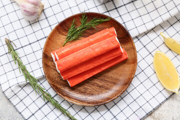 Wooden plate with tasty crab sticks, dill, rosemary and pieces of lemon on white background © Pixel-Shot