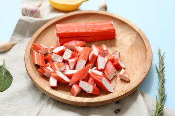 Wooden plate with tasty crab sticks and different spices on blue background © Pixel-Shot