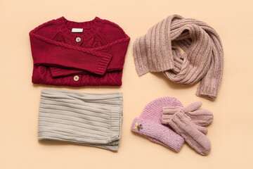 Stylish children's sweater, scarf, trousers, hat and mittens on beige background