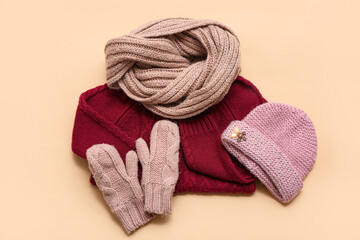 Stylish children's sweater, scarf, hat and mittens on beige background