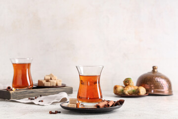Glasses of Turkish tea with delights, cinnamon sticks and cloves on light background