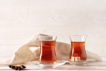 Glasses of Turkish tea with anise stars and sugar cubes on white wooden background