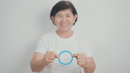 Elderly woman with Blue Circle for World Diabetes Day, Blue November Health month, Diabetes awareness, Blood sugar check, Insulin, Glucose screening, Healthy lifestyle, Chronic disease checkup