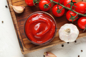 Wooden tray with bowl of tasty ketchup and ingredients on white grunge background, closeup
