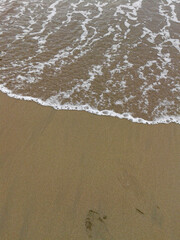 Gentle ocean waves and white foam on the beach