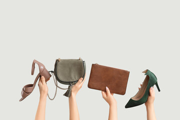 Female hands holding stylish black women's bags and shoes on white background