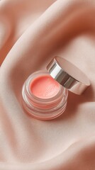 Pink Lip Gloss In A Silver Container On A Pale Pink Fabric