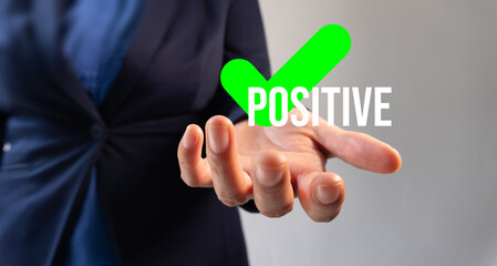 Businesswoman's hand holding a green check mark with the word "Positive"